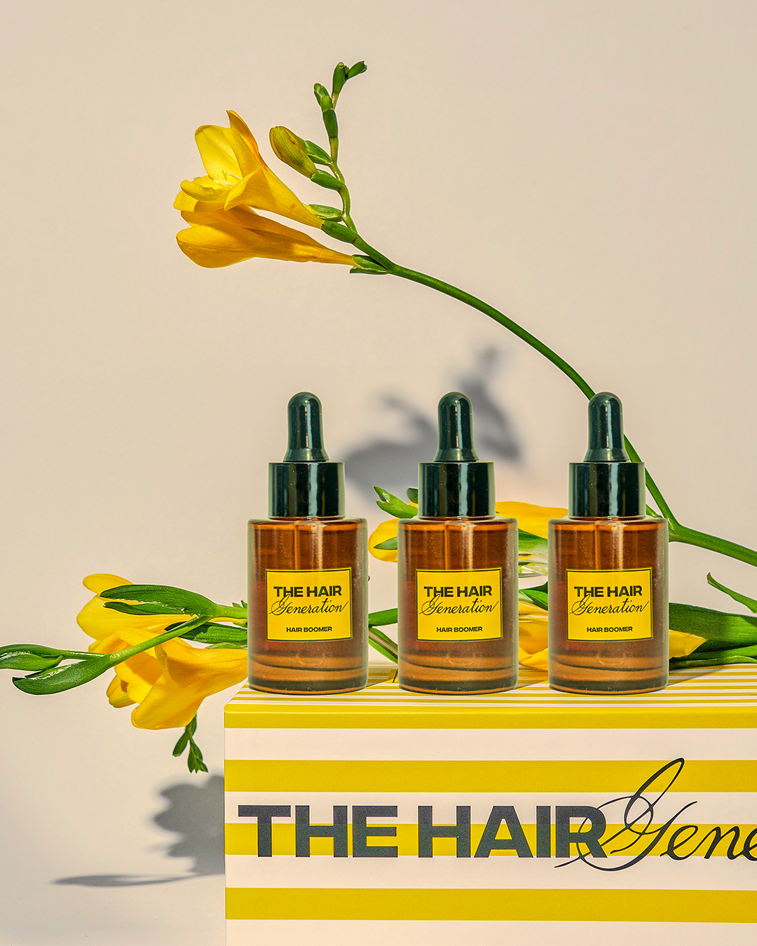 THREE PACK: 3 Hair Boomer con gotero sobre caja decorativa y flores amarillas, tratamiento capilar para fortalecer y hacer crecer el cabello.